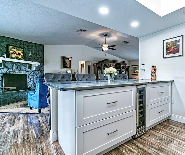 kitchen with white cabinets, dark hardwood / wood-style flooring, wine cooler, kitchen peninsula, and ceiling fan