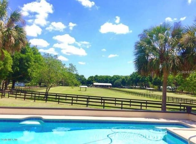 view of pool featuring a rural view and a yard