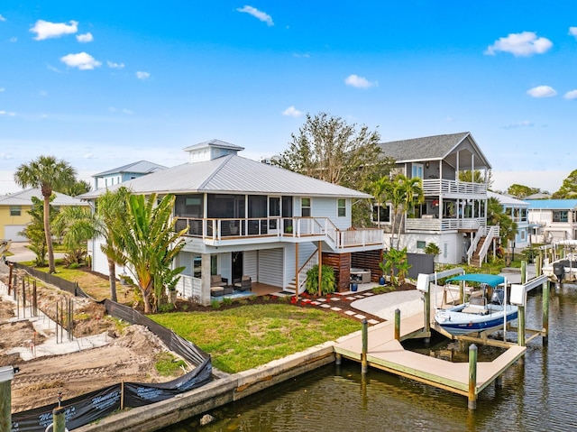 rear view of house with a water view, a yard, a patio area, and a sunroom