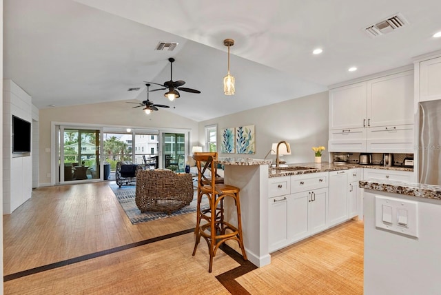 kitchen with sink, white cabinets, a kitchen island with sink, and stone counters