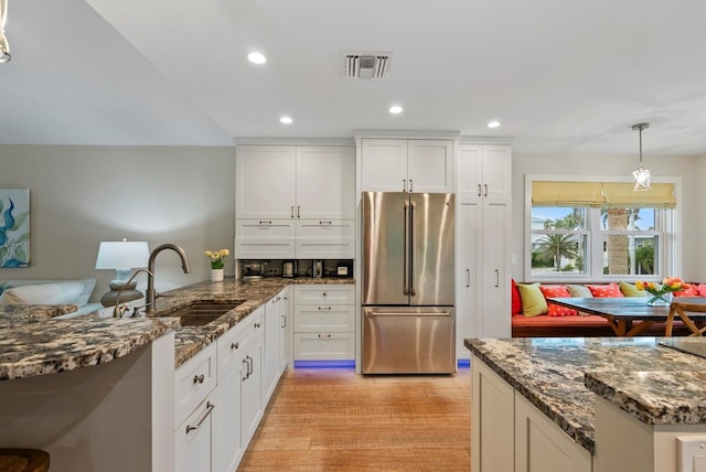 kitchen with sink, decorative light fixtures, white cabinetry, and high end fridge