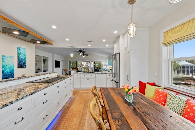 kitchen featuring vaulted ceiling, white cabinetry, high end fridge, dark stone countertops, and black electric cooktop