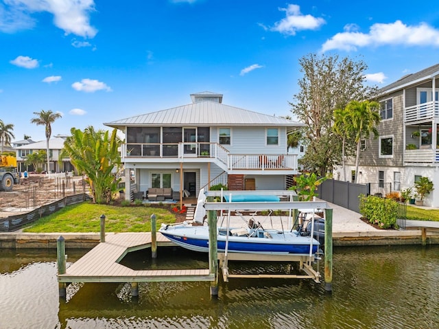 back of property with an outdoor living space, a water view, and a sunroom