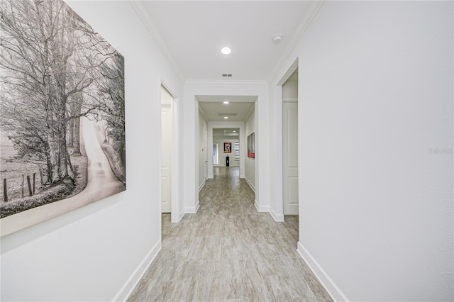 hallway featuring crown molding and light hardwood / wood-style floors