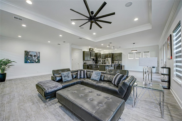 living room featuring ceiling fan, crown molding, and a tray ceiling