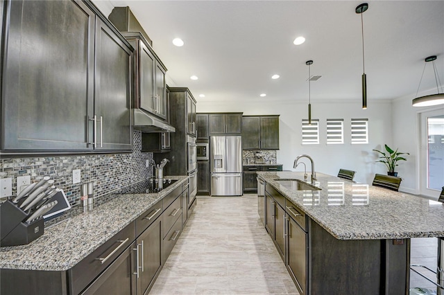 kitchen with sink, hanging light fixtures, stainless steel fridge with ice dispenser, and a kitchen island with sink