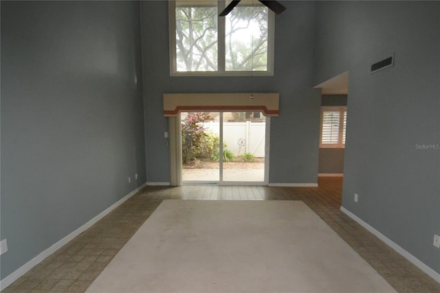 tiled foyer with ceiling fan, a towering ceiling, and a wealth of natural light