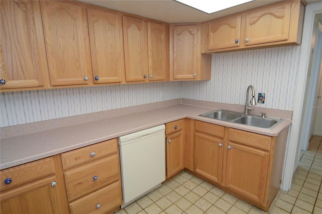 kitchen featuring white dishwasher, sink, and light brown cabinetry