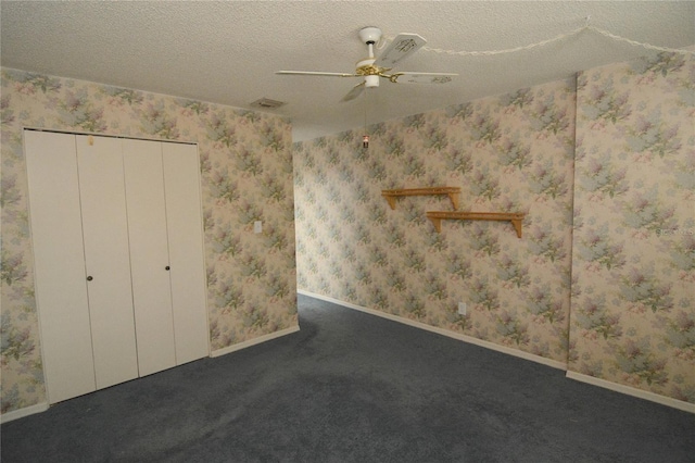 unfurnished bedroom featuring dark colored carpet, a textured ceiling, a closet, and ceiling fan