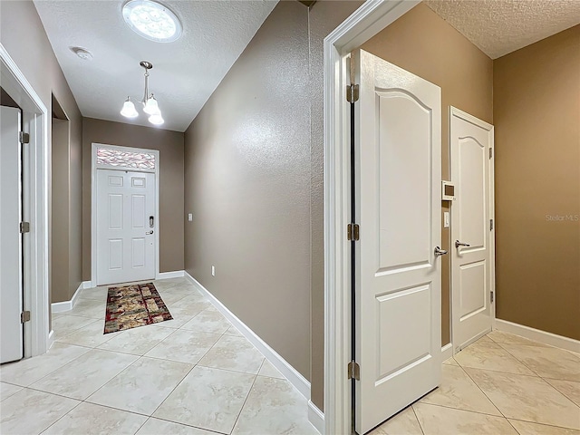 foyer entrance with a textured ceiling, a chandelier, and light tile patterned flooring