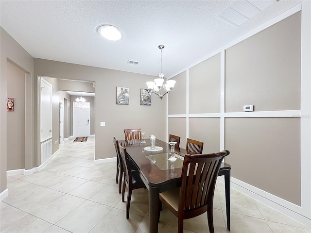 tiled dining space featuring a textured ceiling and a notable chandelier