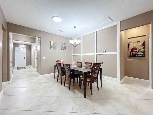 dining space featuring a textured ceiling, light tile patterned floors, and a chandelier