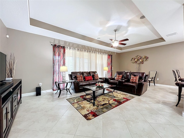 tiled living room featuring ceiling fan and a raised ceiling