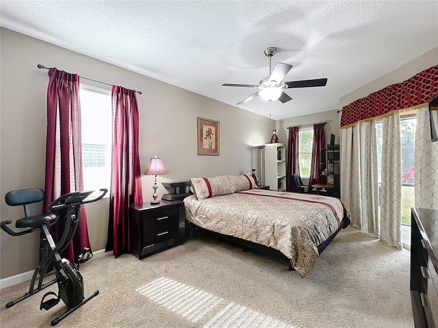 bedroom featuring ceiling fan, light colored carpet, multiple windows, and a textured ceiling