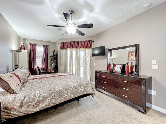 bedroom with ceiling fan, light carpet, and a textured ceiling