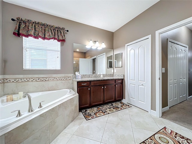 bathroom with tiled tub, vanity, and tile patterned flooring