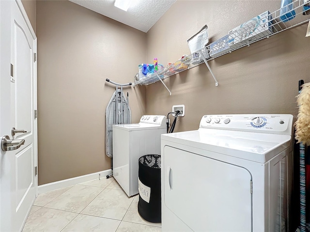 laundry room featuring light tile patterned floors, washing machine and clothes dryer, and a textured ceiling