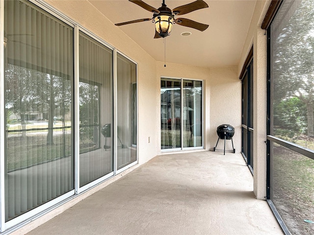 unfurnished sunroom featuring ceiling fan and plenty of natural light