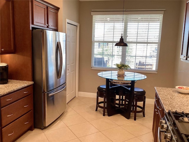 kitchen with light stone countertops, stainless steel fridge, range, and light tile patterned flooring