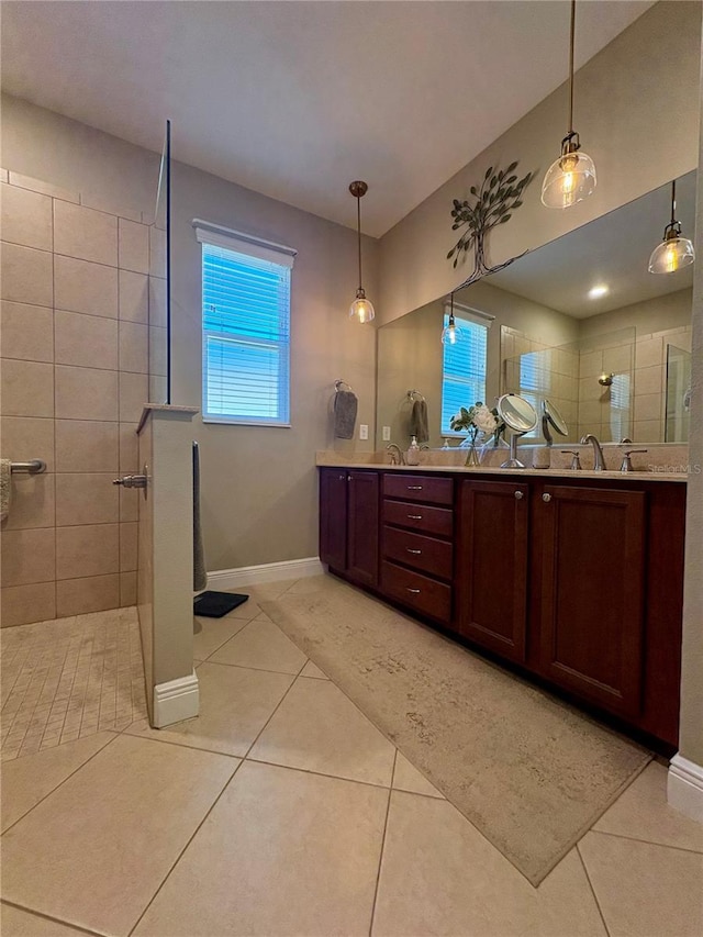 bathroom with tiled shower, vanity, and tile patterned flooring