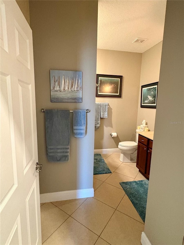 bathroom with toilet, vanity, and tile patterned floors