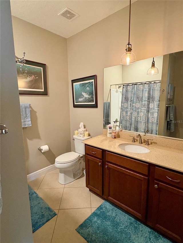 bathroom featuring toilet, tile patterned floors, vanity, and curtained shower