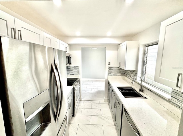 kitchen featuring appliances with stainless steel finishes, decorative backsplash, white cabinets, and sink