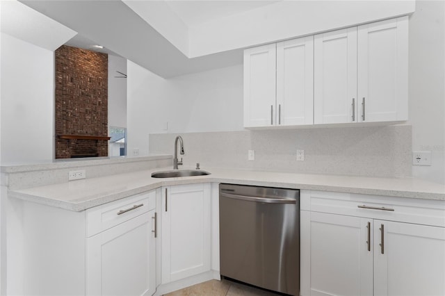 kitchen with stainless steel dishwasher, white cabinets, sink, and tasteful backsplash