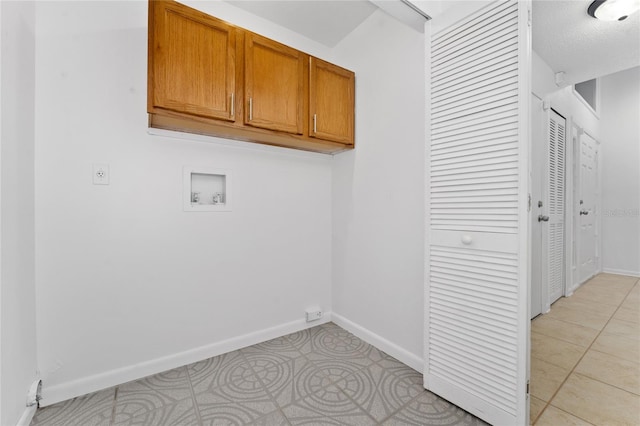 clothes washing area with washer hookup, cabinets, and light tile patterned flooring