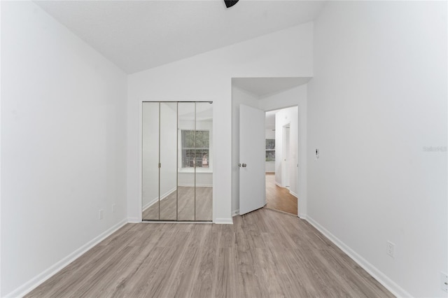 unfurnished bedroom with light wood-type flooring, a closet, and vaulted ceiling