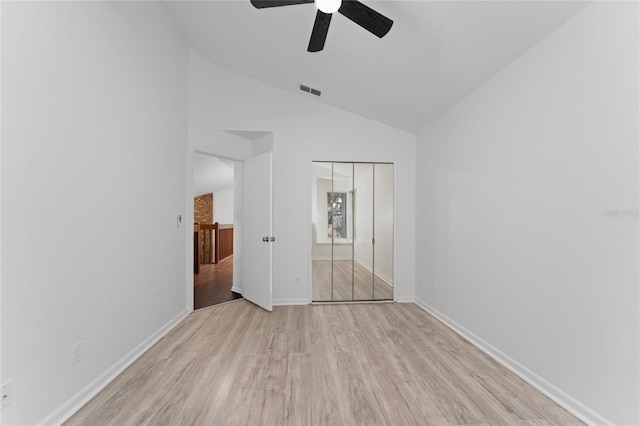 unfurnished bedroom featuring ceiling fan, light hardwood / wood-style floors, a closet, and vaulted ceiling