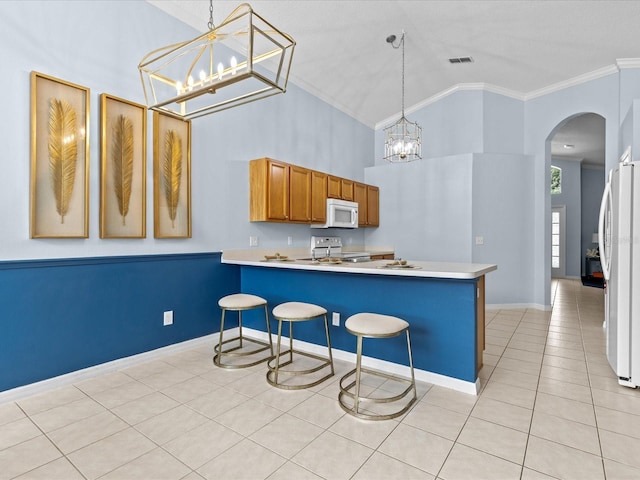 kitchen with light tile patterned floors, kitchen peninsula, white appliances, hanging light fixtures, and crown molding