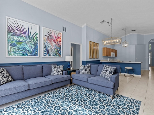 living room with light tile patterned flooring, ornamental molding, lofted ceiling, and an inviting chandelier