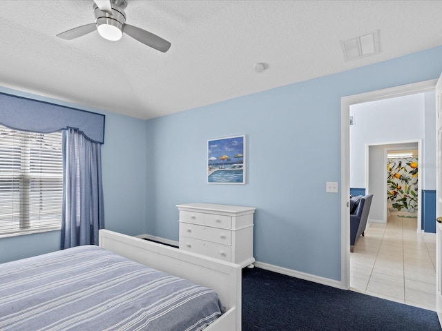 bedroom with ceiling fan, light tile patterned floors, and a textured ceiling