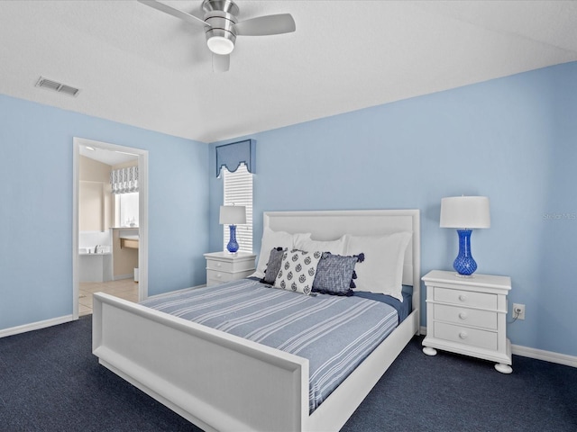 bedroom featuring ceiling fan, dark colored carpet, and ensuite bath