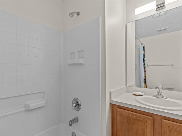 bathroom with a textured ceiling, vanity, and shower / tub combo