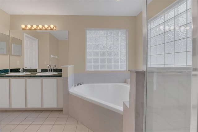 bathroom featuring vanity, tiled bath, and tile patterned flooring