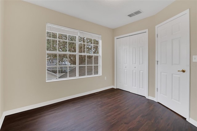 unfurnished bedroom featuring a closet and dark hardwood / wood-style flooring