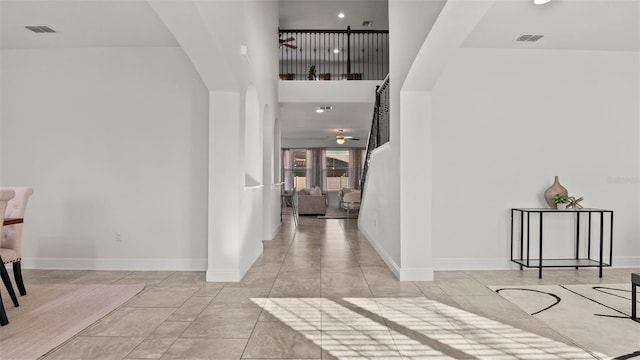 foyer entrance with a high ceiling, ceiling fan, and light tile patterned flooring