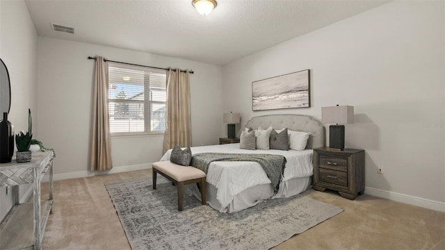 bedroom with light colored carpet and a textured ceiling