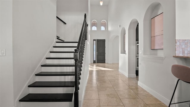 stairs with a towering ceiling and tile patterned flooring