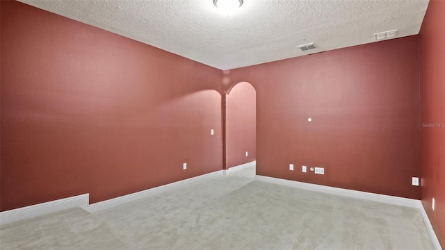 spare room with light carpet and a textured ceiling