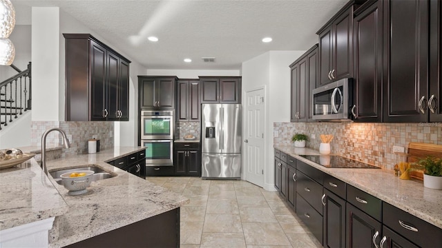 kitchen with light stone countertops, appliances with stainless steel finishes, sink, and decorative backsplash