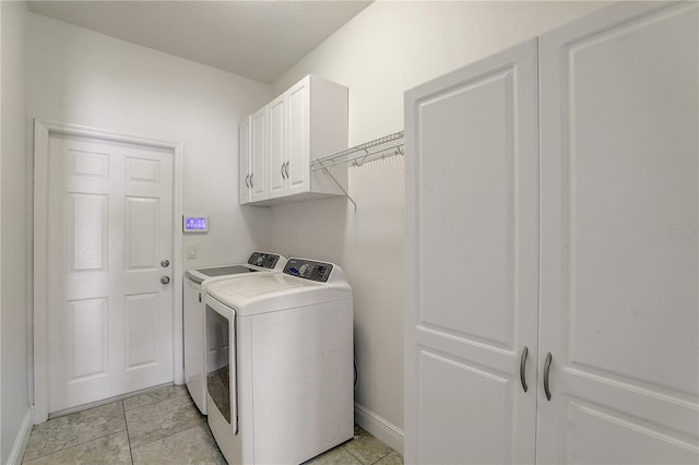 laundry room featuring light tile patterned flooring, cabinets, and separate washer and dryer