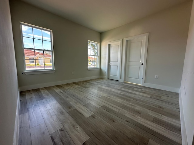 unfurnished bedroom featuring multiple windows and light hardwood / wood-style floors