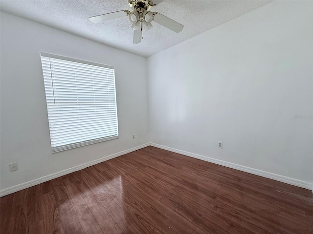 empty room featuring ceiling fan, dark wood-type flooring, and a textured ceiling