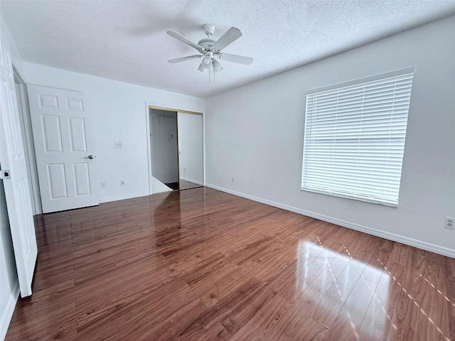 unfurnished bedroom with ceiling fan, dark wood-type flooring, a textured ceiling, and a closet