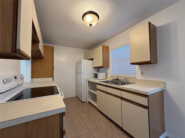 kitchen featuring light tile patterned floors, sink, white appliances, and a textured ceiling