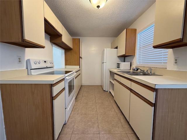 kitchen featuring light tile patterned floors, sink, white appliances, and a textured ceiling