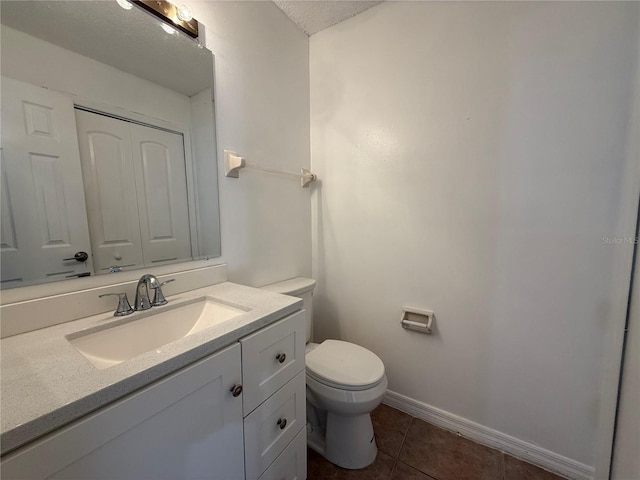 bathroom with a textured ceiling, toilet, tile patterned flooring, and vanity